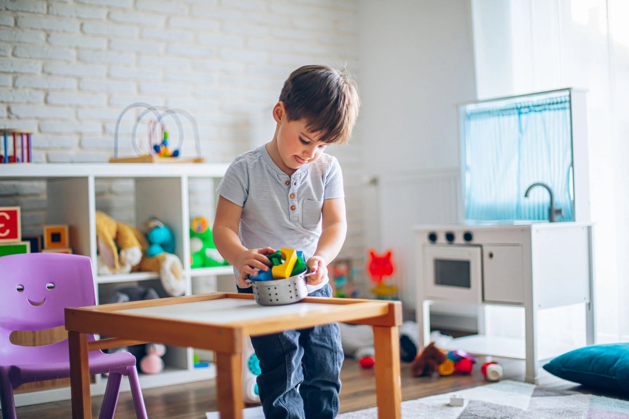 Child playing independently with colorful building toys in bright playroom
